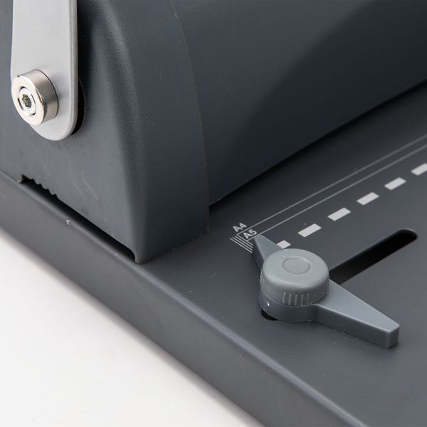 Close-up of a comb binding machine paper guide with measurement markings on a white background