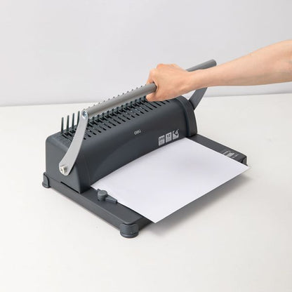 Person using a comb binding machine on a white background
